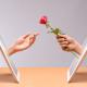 Online dating - handing a red rose out of the tablet screen